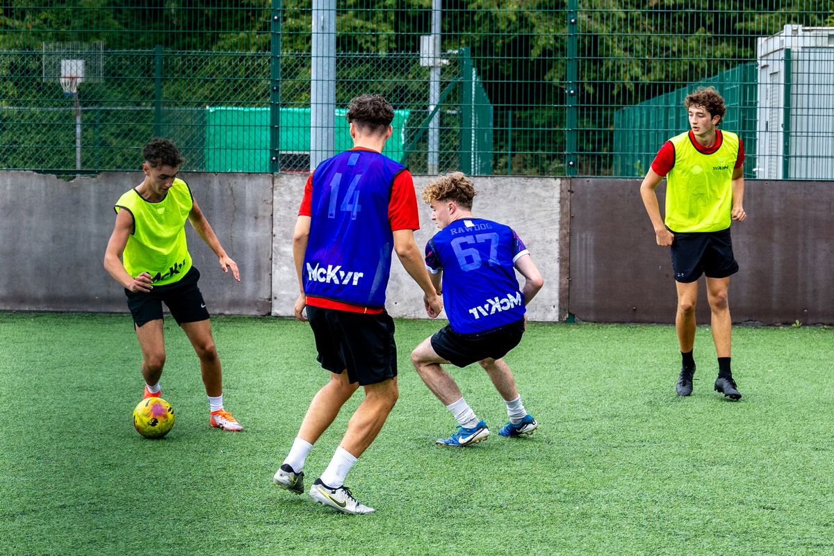 Players in bibs battling for the ball on an astro pitch