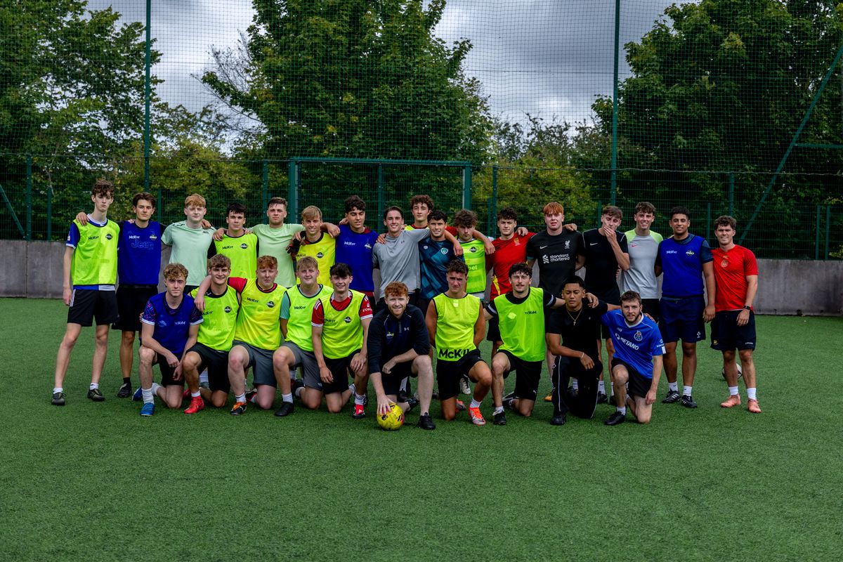 Around thirty players in RIVALZ bibs posing together on the pitch