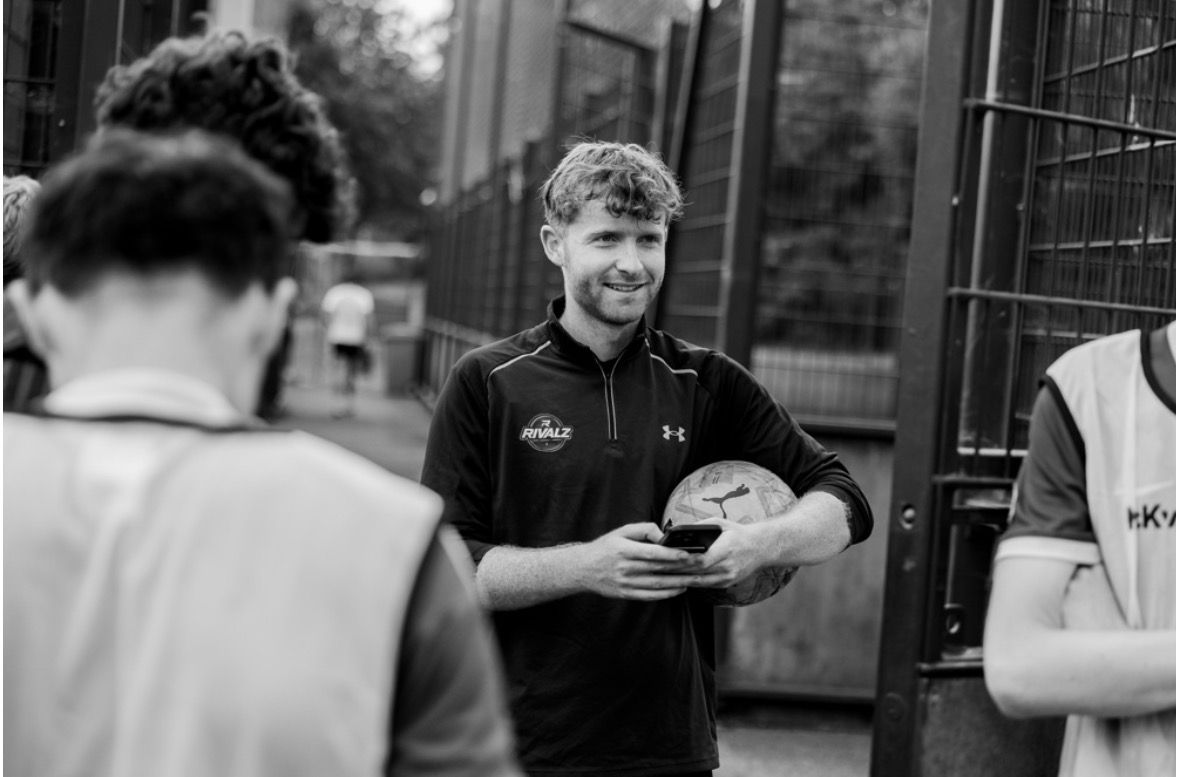 RIVALZ organiser holding a football and checking the fixtures on his phone