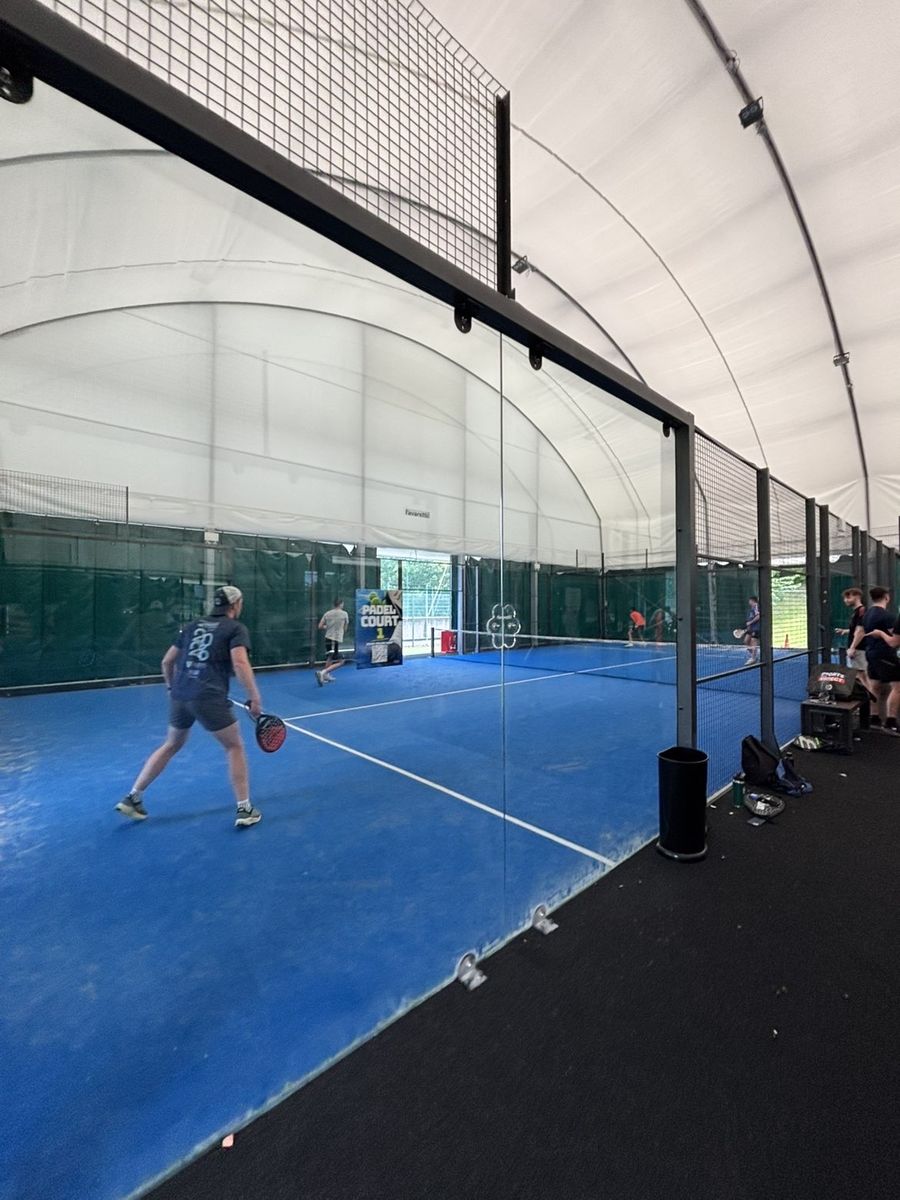 A padel player ready to return a shot on a blue indoor court